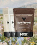 Tre buste da 500g di Beef Protein Grass Fed marca Carnivore Company, gusto cacao e varianti neutre, proteine idrolizzate del manzo animal-based su sfondo paesaggio naturale