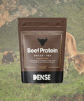 Busta marrone da 500g di Beef Protein Grass Fed gusto cacao del brand Carnivore Company, con mucche al pascolo su prato verde sullo sfondo — proteine del manzo grass fed idrolizzate animal-based