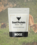 Busta da 500g di Beef Protein Grass Fed gusto vaniglia del brand Carnivore Company, con mucche al pascolo sullo sfondo — proteine del manzo grass fed idrolizzate in polvere