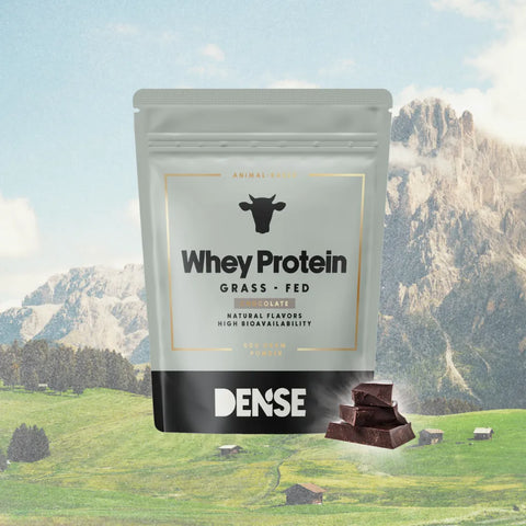 Confezione di proteine Whey grass fed al cioccolato Carnivore Company con sfondo di montagne alpine e pezzi di cioccolato.
